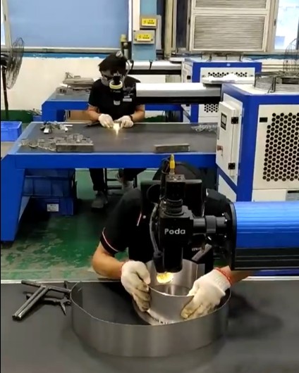 Workers assembling metal sign components at workshop benches