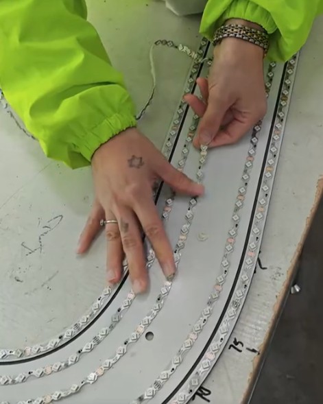 Worker fitting LED modules to a curved sign component